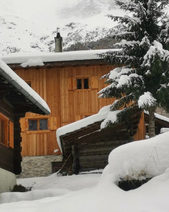 Façade de chalet en lambris de mélèze avec volets, sous la neige à Zinal